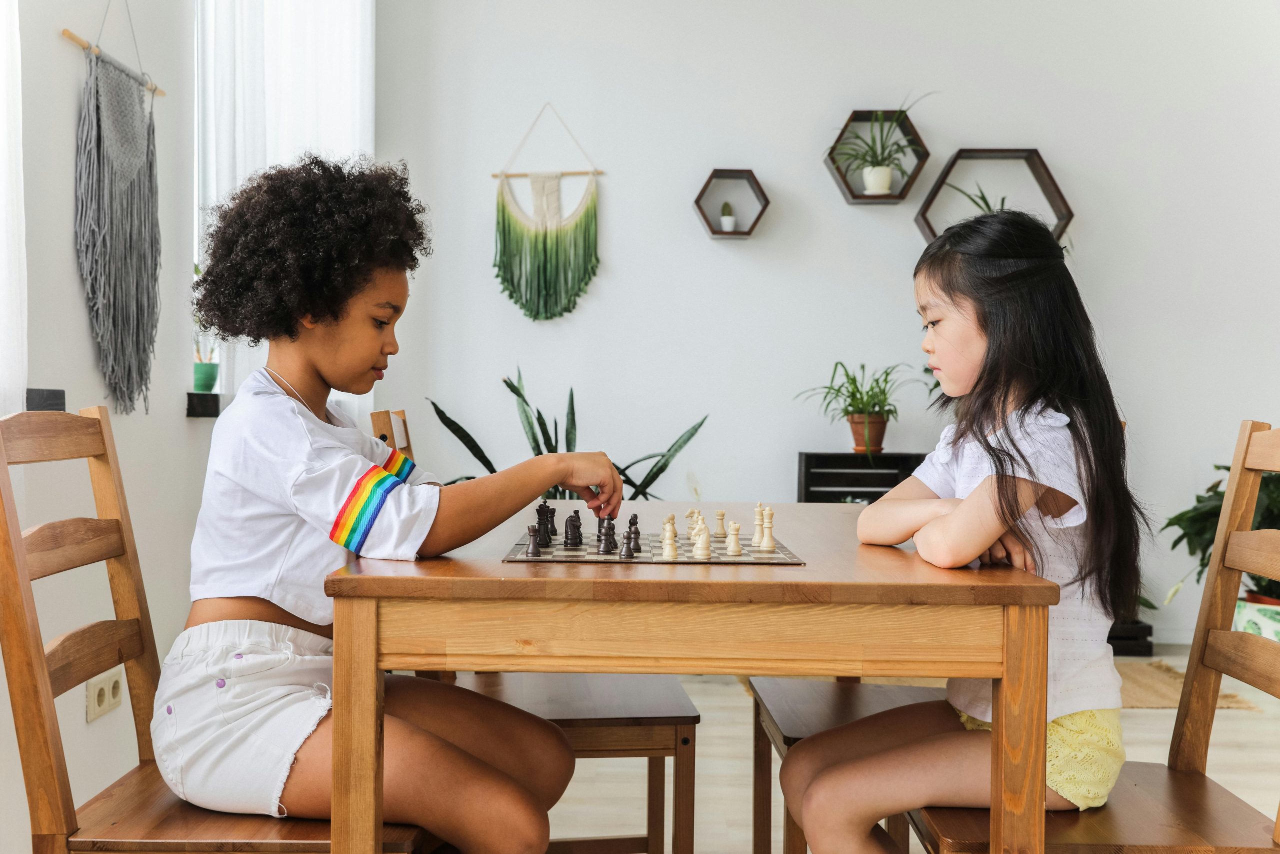 Offering Two diverse children playing chess, focusing intently in a cozy, modern room.