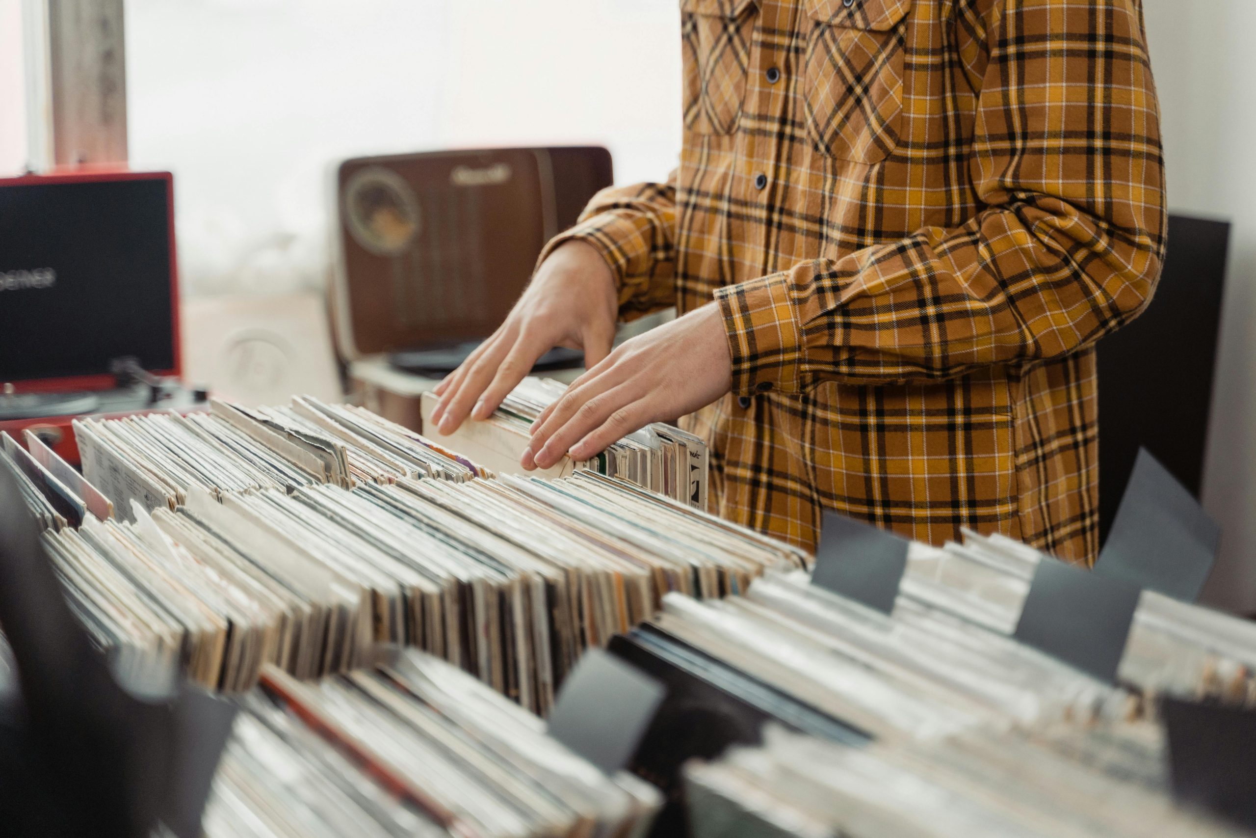 Offering A man looks through vinyl records in a vintage-style music store, emphasizing retro shopping vibes.